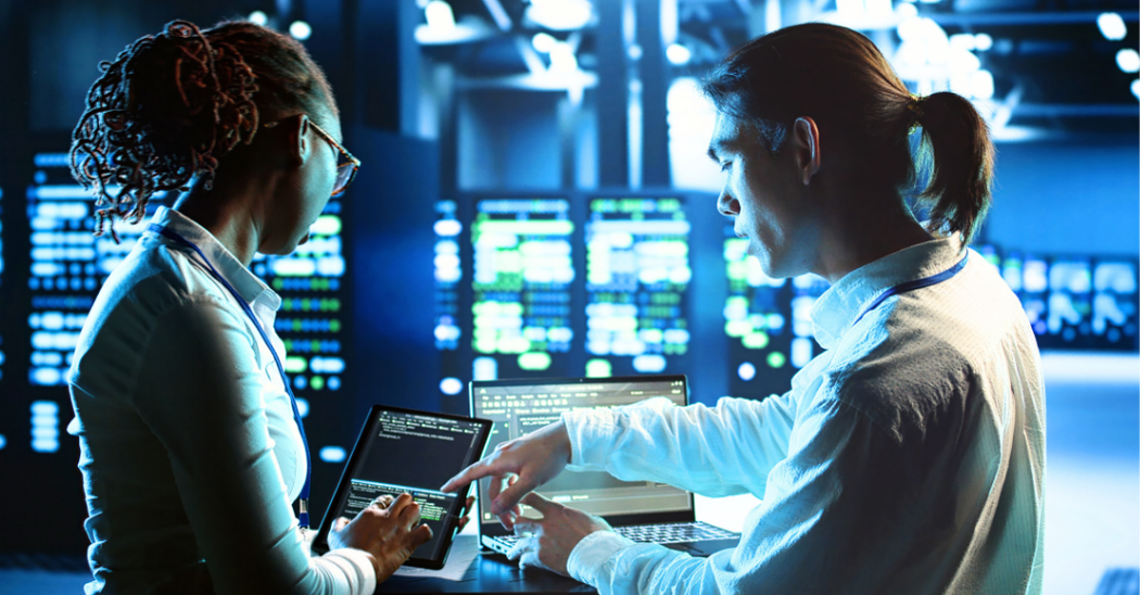 Cybersecurity professionals analyzing data on laptops and tablets in a secure cloud operations center, monitoring network activity and system performance to protect sensitive healthcare information